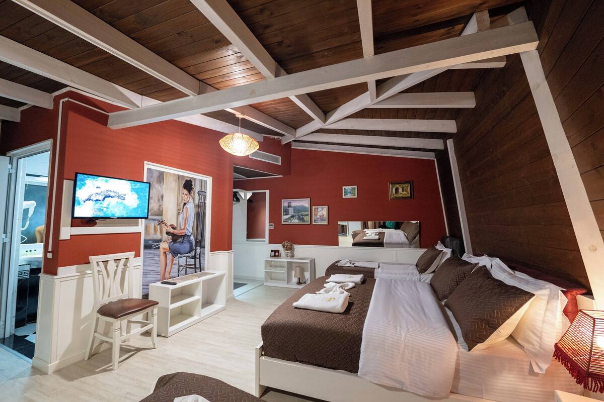 A bedroom with a bed, a desk, a chair, and a television.