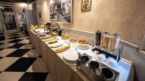 A buffet with various dishes and condiments, a refrigerator, and a decorative wall with framed pictures. - Hotel Aria (Tirana)