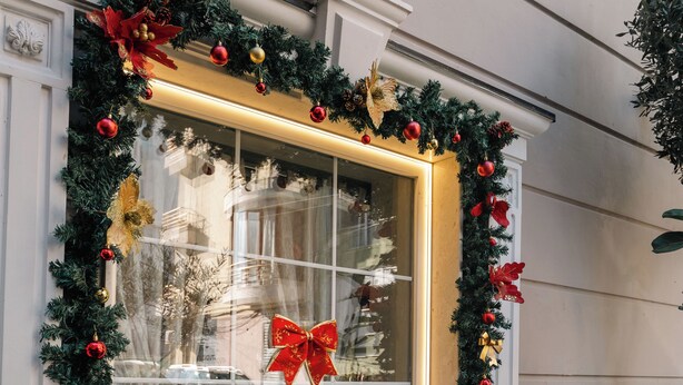 A window with a Christmas wreath and decorations, including a red bow. - Hotel Aria (Tirana)