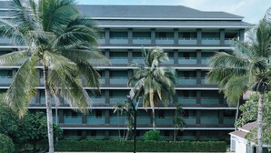 A hotel with a swimming pool, palm trees, and a multi-story building with balconies. - Eastpana 304(R1) Executive Residence (Si Maha Phot)