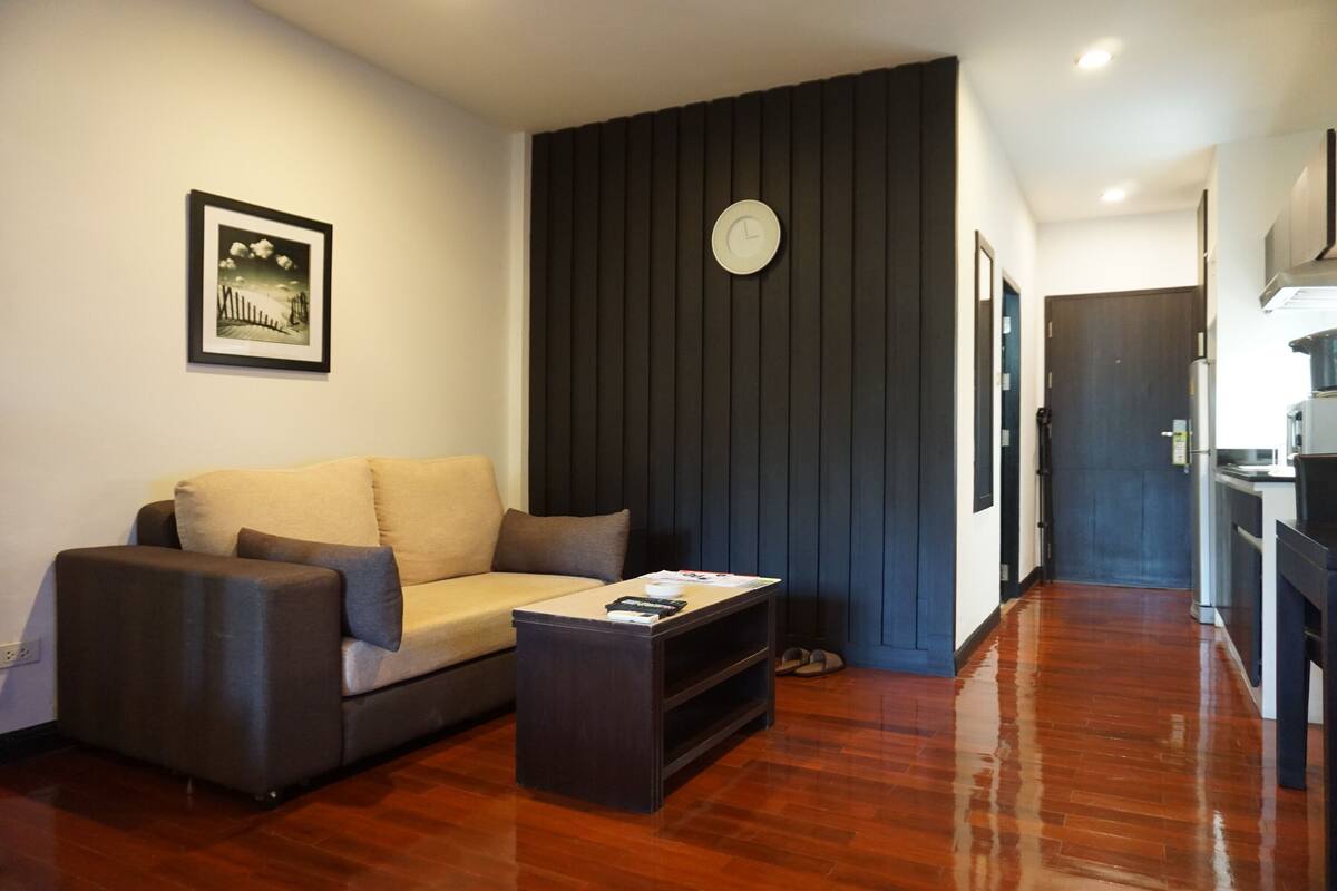 Una sala de estar con un sofá, una mesa de centro, un reloj en la pared y un cuadro enmarcado.