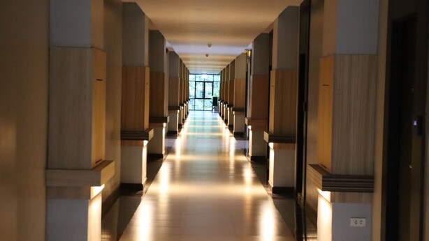 A long, well-lit hallway with a series of doors on either side, leading to rooms. - Eastpana 304(R1) Executive Residence (Si Maha Phot)