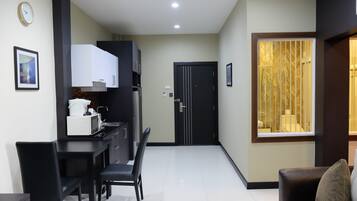 A modern kitchen with white cabinets, a microwave, and a dining area with black chairs.