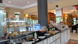 A breakfast buffet area with various food items, a coffee machine, and a flower arrangement. - Eastpana 304(R1) Executive Residence (Si Maha Phot)