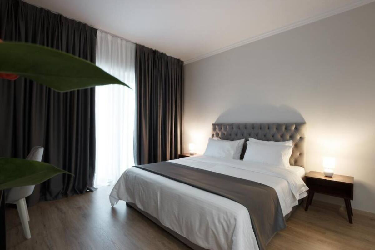 A neatly arranged bedroom with a large bed, a bedside table with a lamp, and a chair.