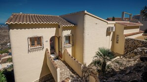 A building with a tiled roof, a balcony, and a stone wall.