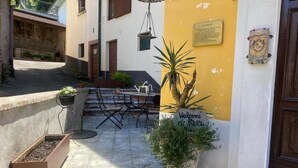 A courtyard with a table and chairs, a planter with a sign, and a building with a plaque.