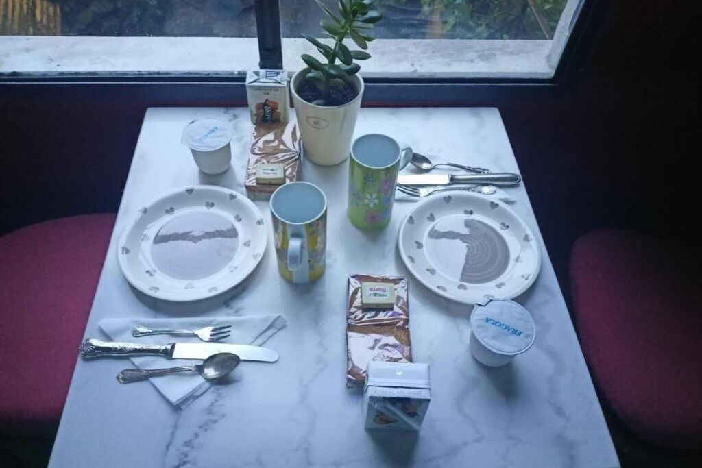 Ett bord dukat med tallrikar, koppar, bestick och förpackade matvaror.