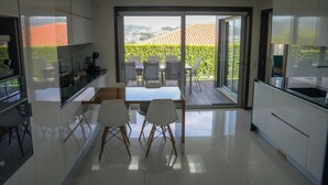 Une cuisine moderne avec un coin repas, de grandes fenêtres et une vue sur l’extérieur.