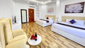 Une chambre d’hôtel avec deux lits, un canapé, une petite table avec une bouteille et des verres, et un plancher en bois.