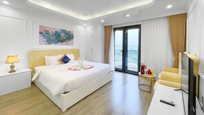 Une chambre d’hôtel comprenant un lit, une table de chevet, une lampe, des œuvres d’art et un balcon avec des rideaux.