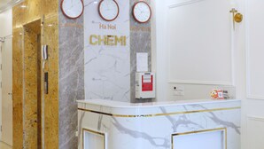 Un espace d’accueil avec des murs en marbre, des horloges et un comptoir de réception.