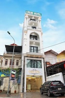 Um hotel chamado CHEMI HOTEL com uma placa chamativa, fachada moderna e um carro estacionado em frente.