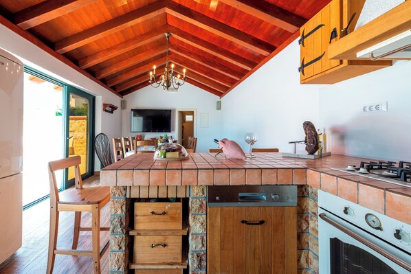 Una cocina con una isla de piedra, armarios de madera, estufa a gas y lavavajillas integrado.