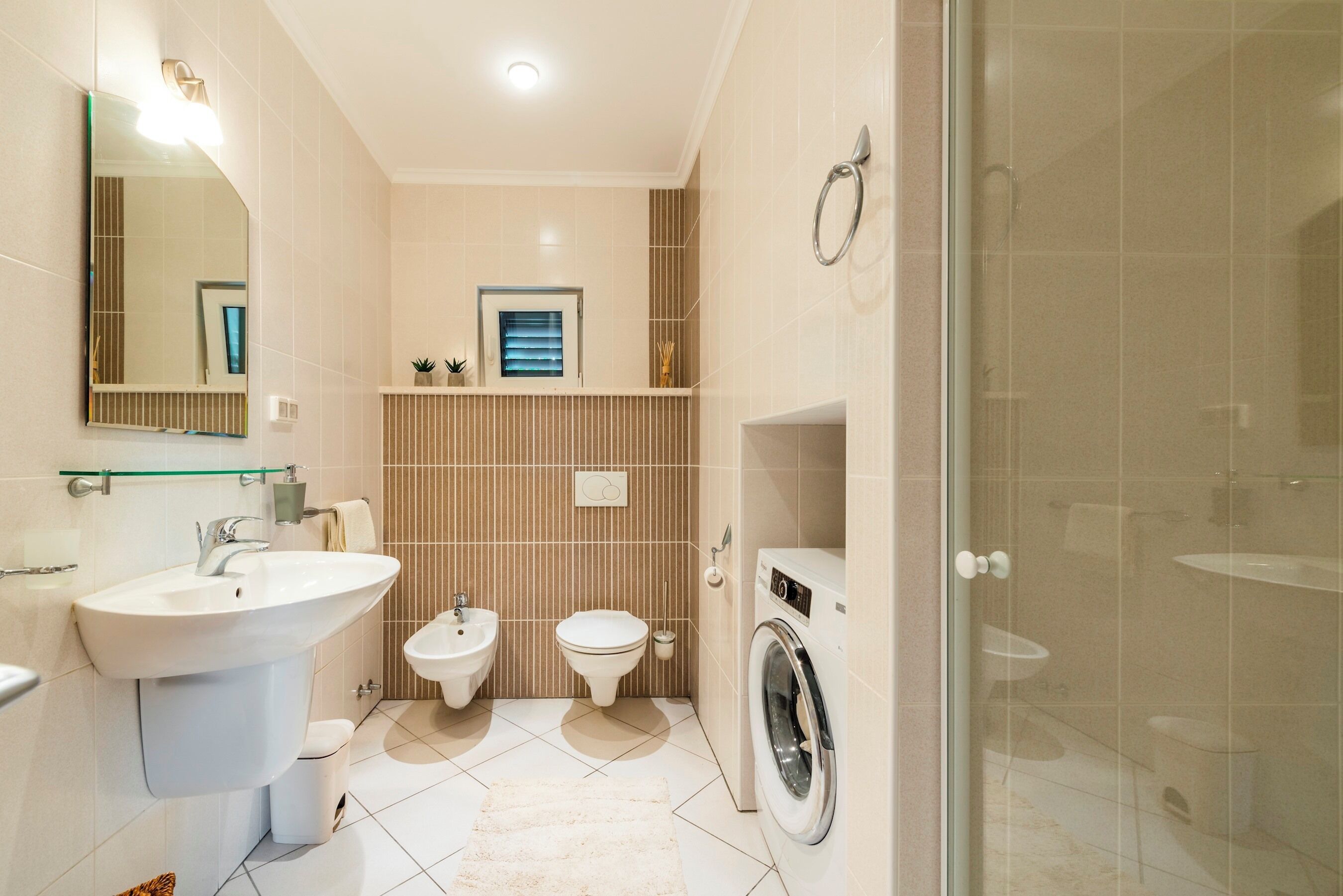 Une salle de bain compacte comprenant un lavabo, un bidet, des toilettes et un lave-linge.