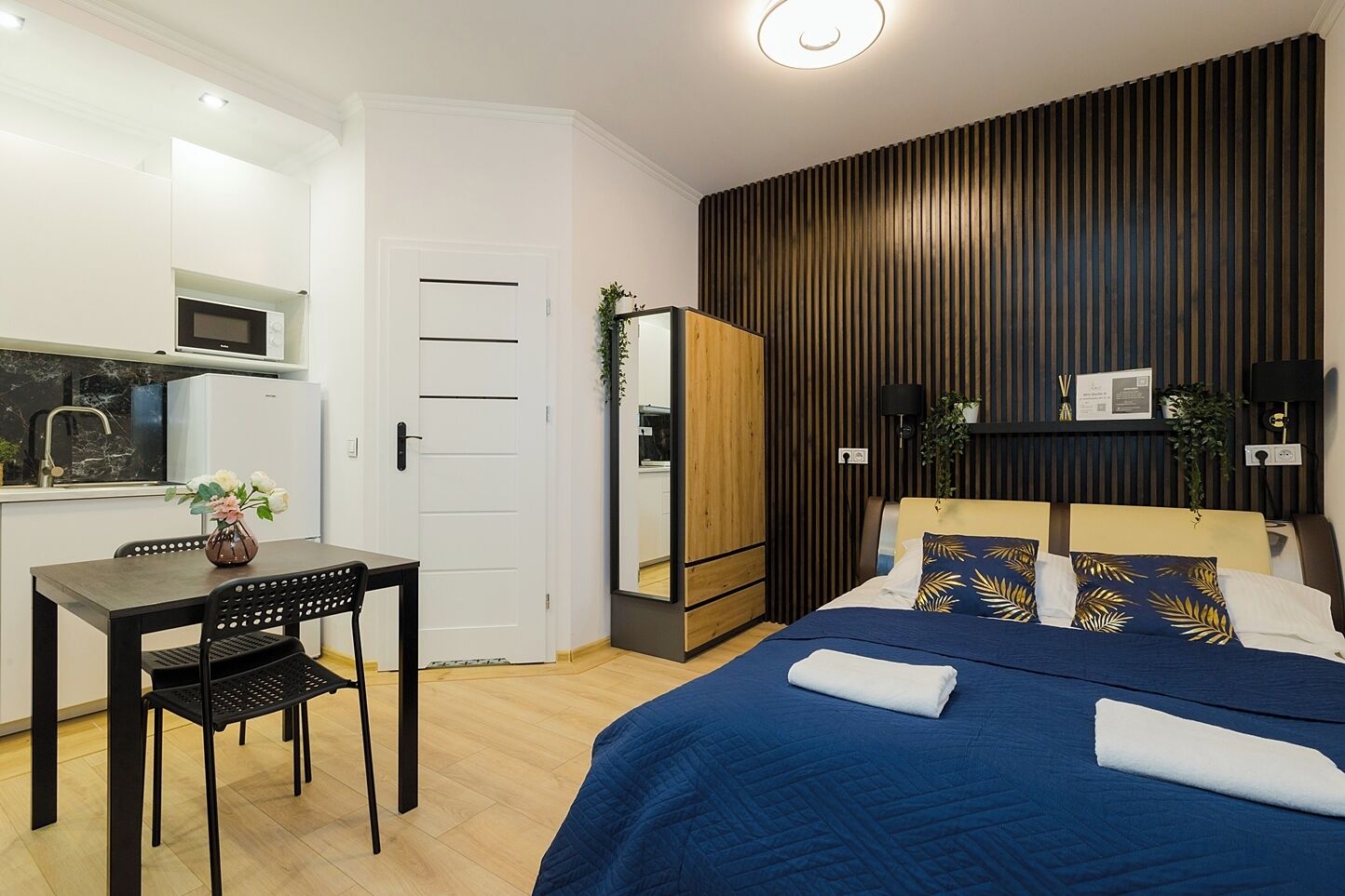 A modern bedroom with a large bed, a bedside table, and a desk with a chair.
