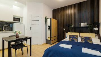 A modern bedroom with a large bed, a bedside table, and a desk with a chair.