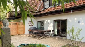 A patio with a wooden deck, a table with chairs, and a small garden area with a planter. - Munich center just a 10-minute subway ride away: 130 m², 4 bedrooms, 2 bathrooms (München)