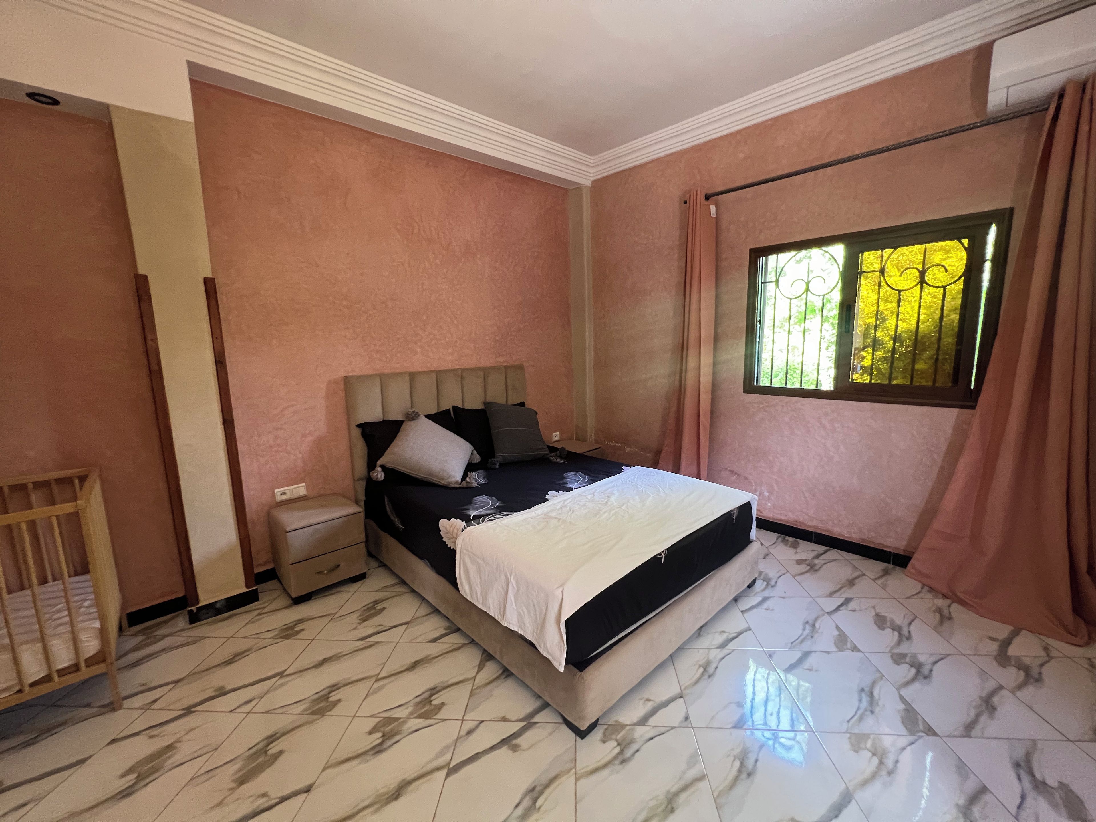 Een slaapkamer met een bed, nachtkastje en een raam met tralies.
