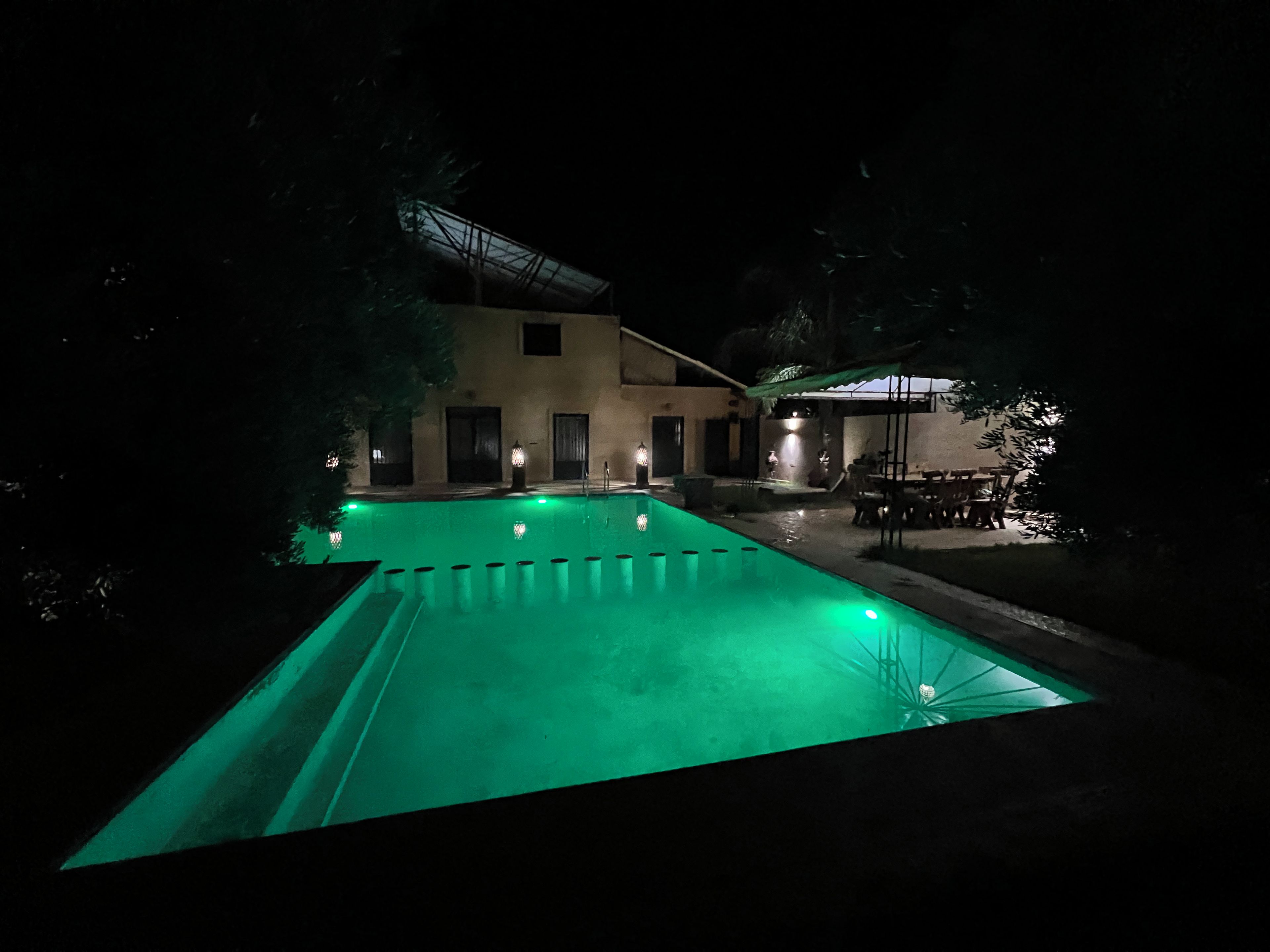 A nighttime view of a swimming pool area with a building in the background.