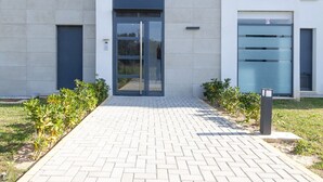 A modern building with a paved entrance, large windows, and a glass door. - Samos Apartment (Badia de Xàbia)