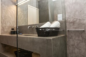 A modern bathroom with a large mirror, a sink, and a towel rack.