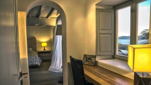 A cozy room with a wooden desk, a lamp, and a bed with a canopy. - Casa di Mare: Luxury and Breathtaking Views in Mykonos (Mykonos)