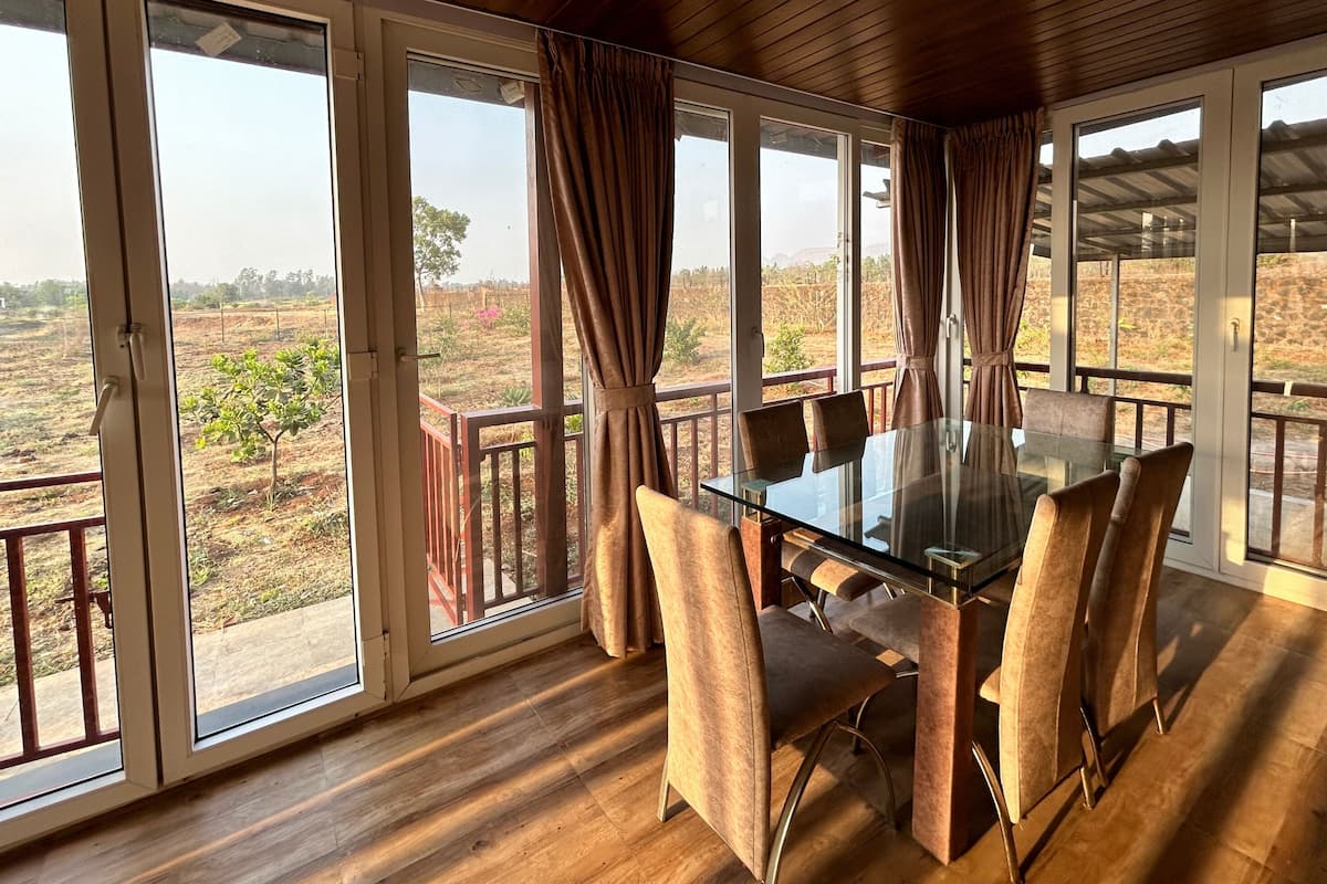 Enjoy a room with a large table, six chairs, and expansive windows offering a view of the outdoor landscape.