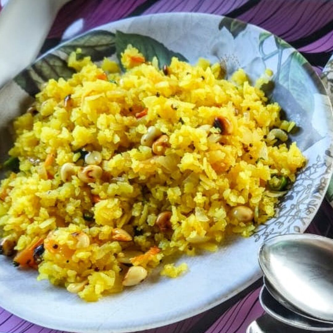 A bowl of yellow rice with nuts and vegetables.