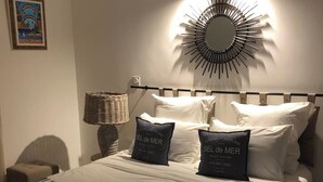 A neatly made bed with pillows labeled "SEL de MER" and a wall-mounted circular light fixture. - Maxima Sunset KONTIKI 4 pers (Sainte-Maxime)