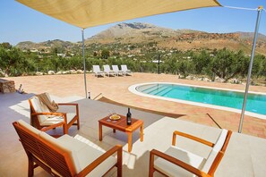 A poolside area with lounge chairs, a table with a bottle and glasses, and a view of mountains. - VILLA NINFA (Castellammare del Golfo)