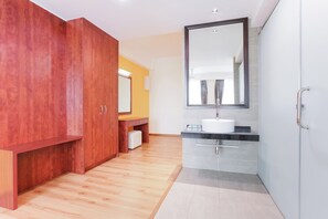Ein modernes Badezimmer mit Holzschränken, einem großen Spiegel und einem Waschbecken.