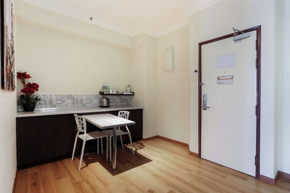 A small kitchen with a white table and chairs, a dark wooden cabinet, and a tiled backsplash.