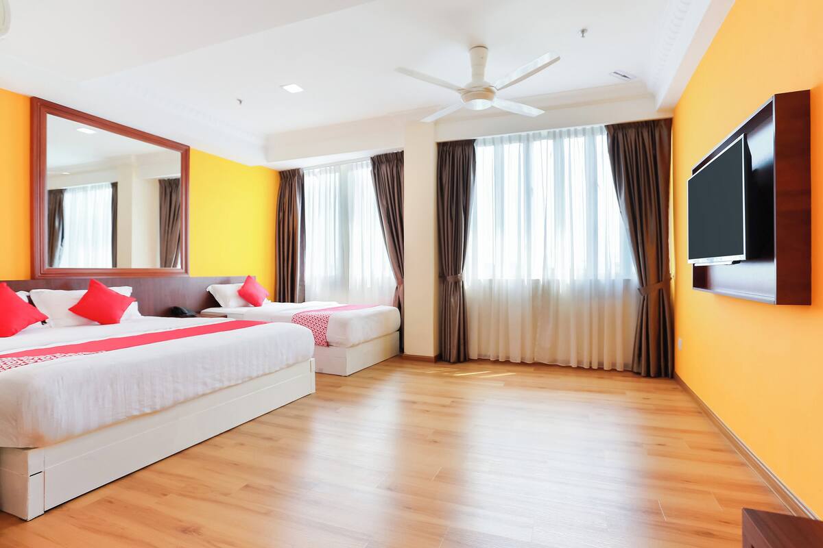 A hotel room with a large bed, a smaller bed, a TV, and a ceiling fan.