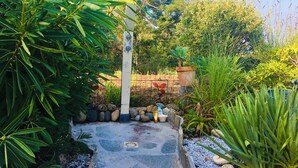 Ein Gartenweg mit Metallzaun, Blumentöpfen und einem Betonbau.