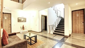 Un hall d’entrée spacieux avec un escalier, un canapé, une table basse et une statue.