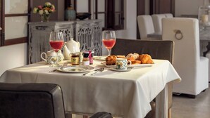 A dining area with a table set for two, featuring a white tablecloth, a teapot, cups, and pastries.