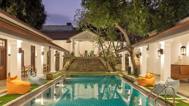 A pool area with a clear view of the pool, lounge chairs, and a staircase leading to an upper level.