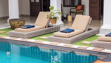Un espace aménagé au bord de la piscine, avec des chaises longues, une plante en pot et un grand vase décoratif.