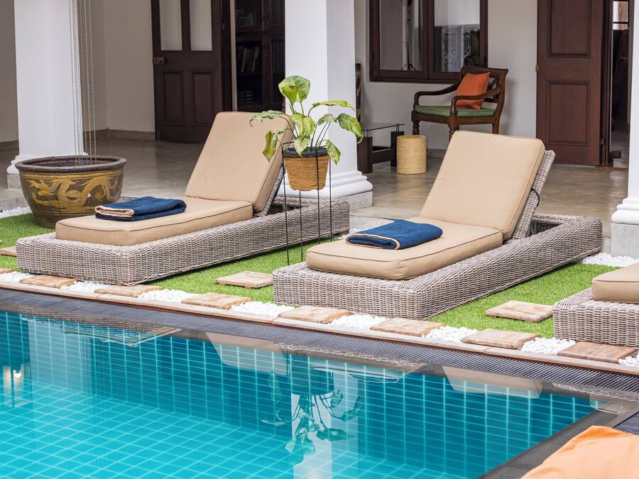 Un espace aménagé au bord de la piscine, avec des chaises longues, une plante en pot et un grand vase décoratif.