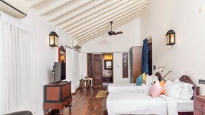 A bedroom with a bed, a TV, a desk, and a wardrobe.