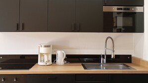 Een moderne keuken met donkere kastjes, een roestvrijstalen spoelbak, een koffiezetapparaat en een waterkoker.