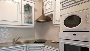 A kitchen with white cabinetry, a stainless steel sink, a microwave, and a built-in oven.
