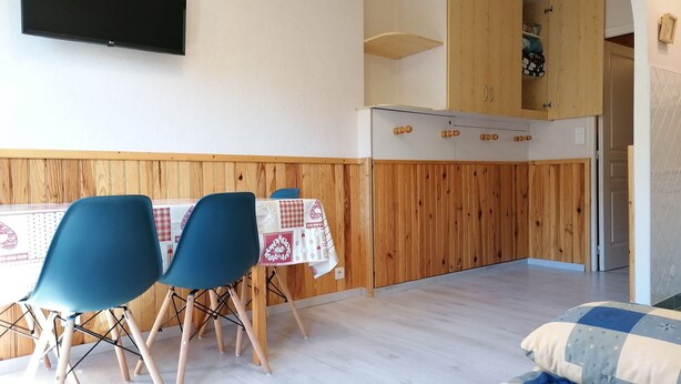 A compact living space with a dining area, kitchenette, and a bed.