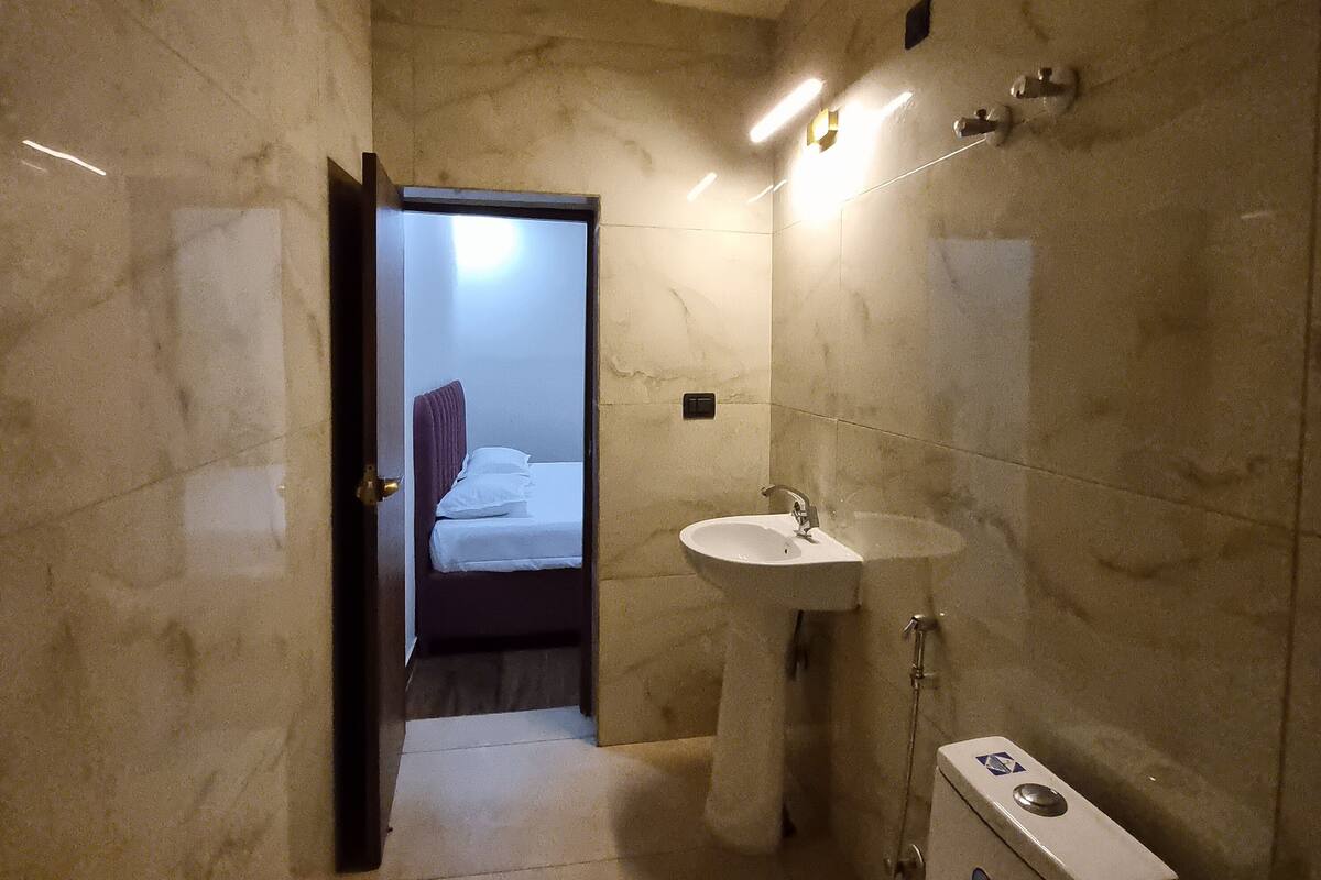 A modern bathroom with a marble floor, a pedestal sink, and a toilet.