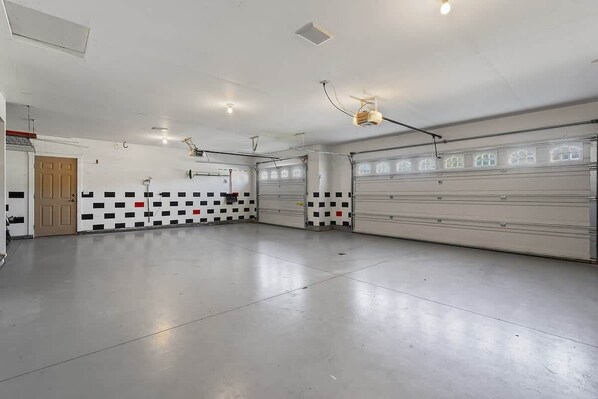 A spacious indoor parking garage with multiple garage doors, a checkered wall pattern, and overhead lighting.