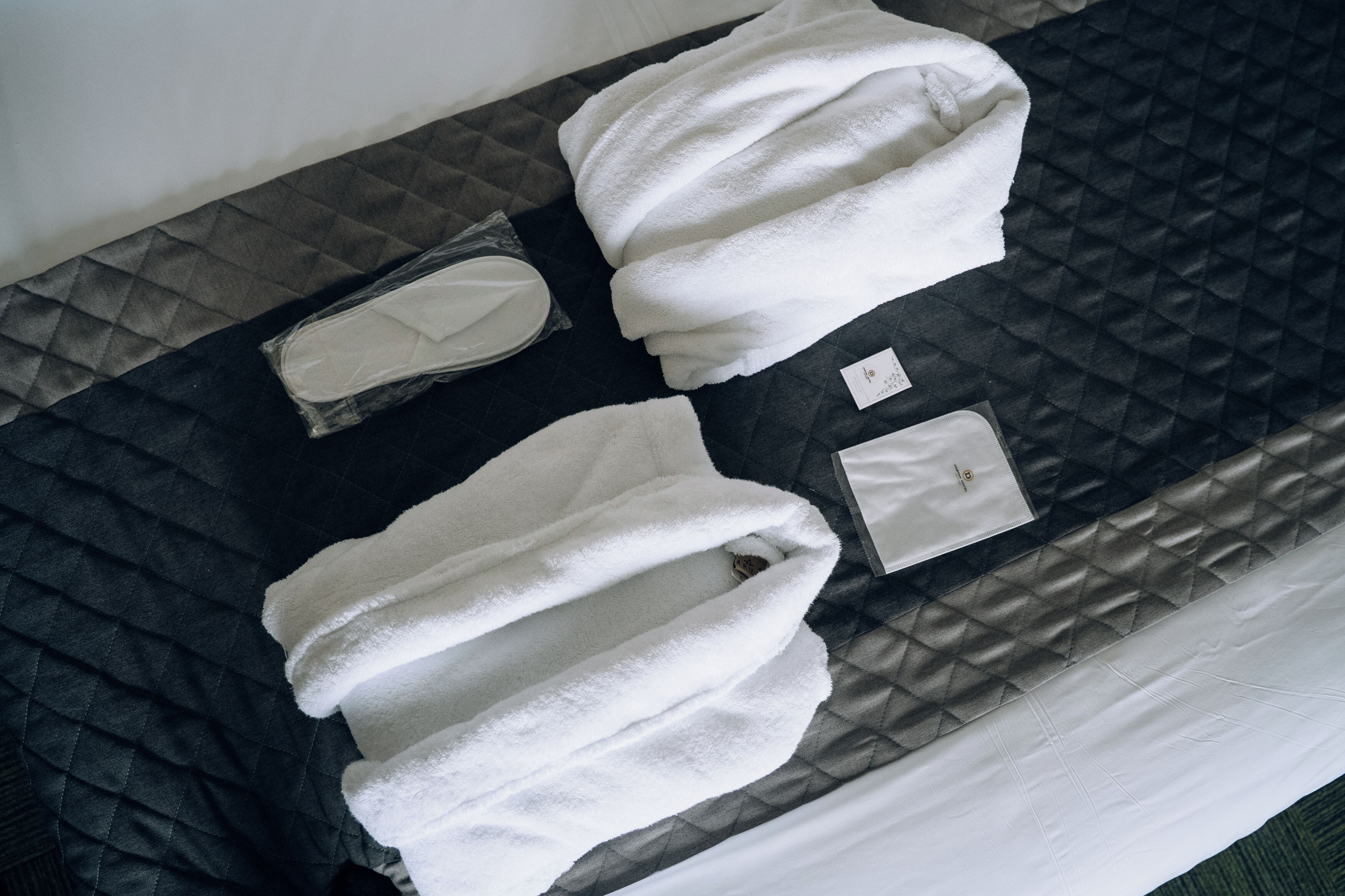 Ein ordentlich gemachtes Bett mit einer gesteppten Decke, einem weißen Kopfkissen und einer kleinen weißen Kopfhaube.