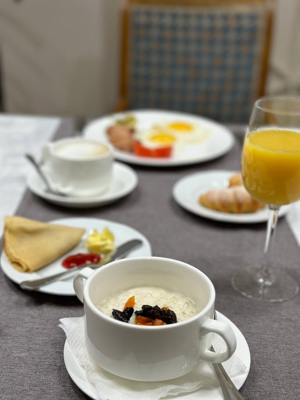 A breakfast setting with a bowl of oatmeal, a croissant, and a glass of orange juice on a table.