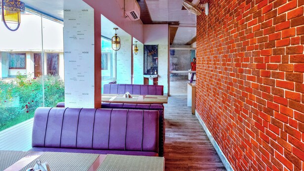 Un restaurante moderno con pared de ladrillo, asientos morados y una pared con la carta.