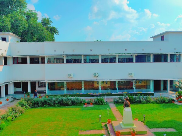 A multi-story building with a central courtyard, potted plants, and a statue.